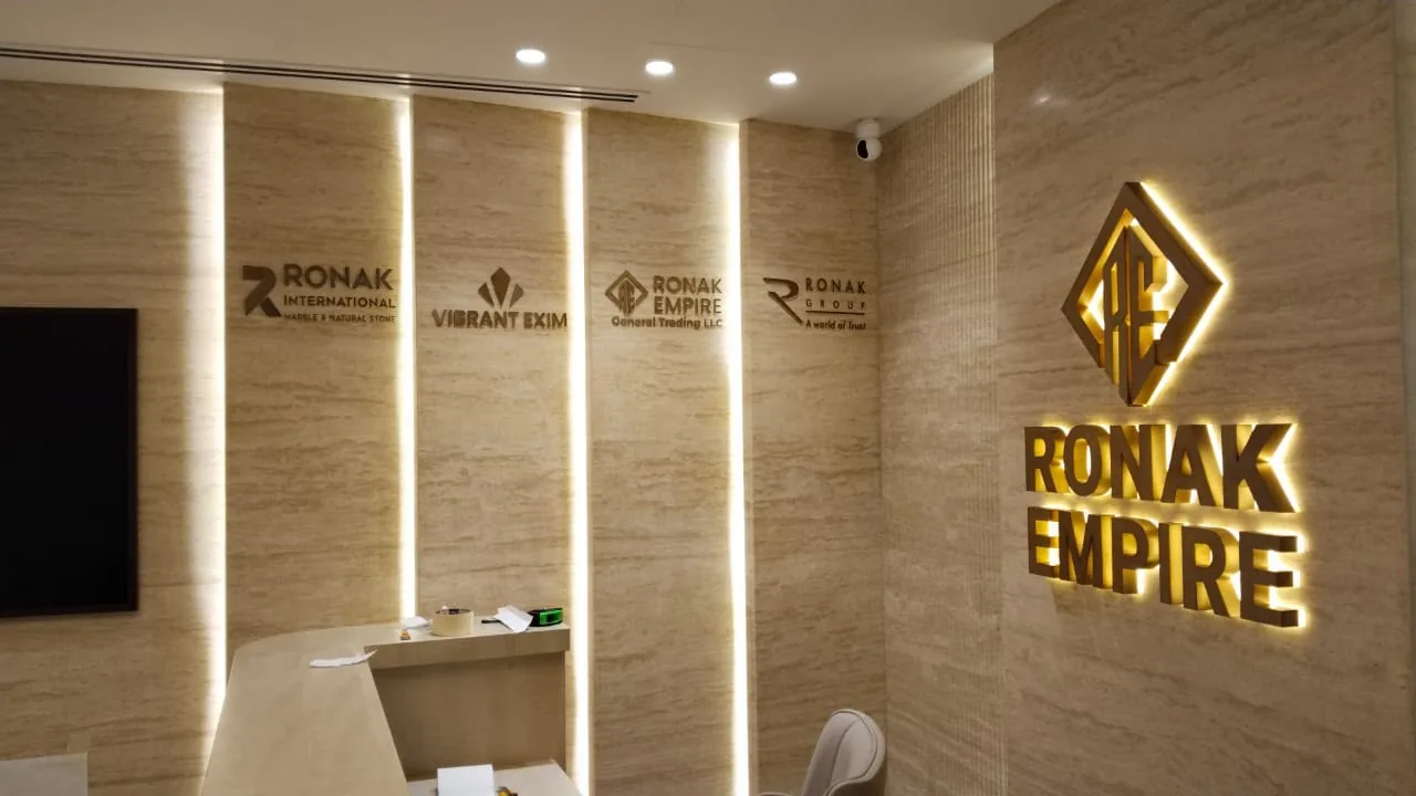 Ronak Empire reception with backlit 3D lettering on a travertine feature wall