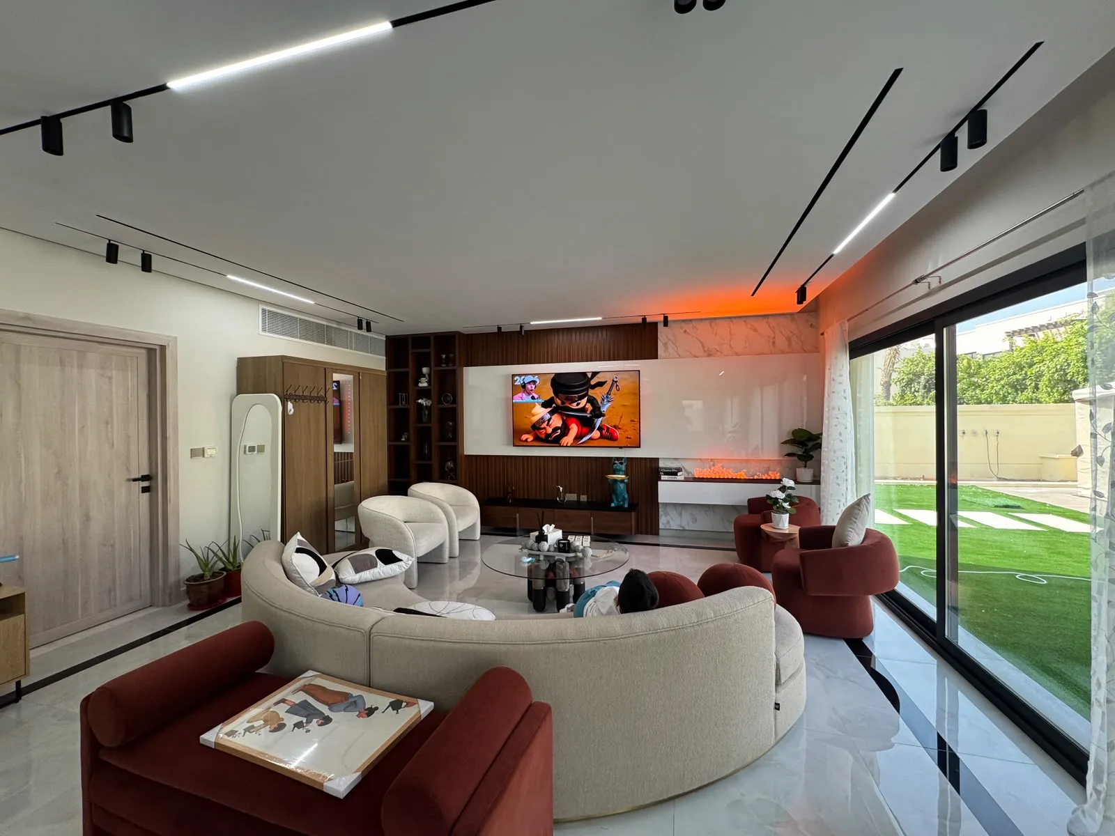 Villa living room in Jumeirah Village Triangle with a built-in TV wall, concealed LED lighting and curved seating